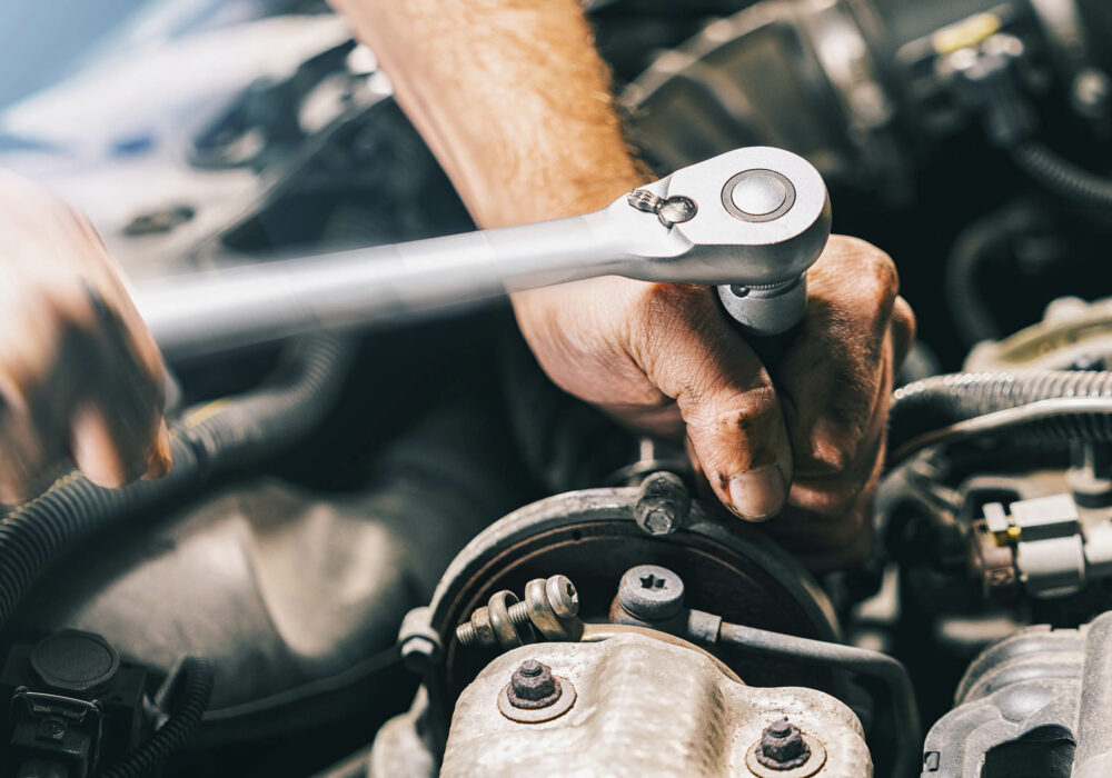 Hands of car mechanic in auto repair service with wrench